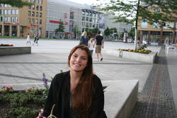 Andrea aus Spanien nimmt auf einer Bank vor der Hochschule Platz.