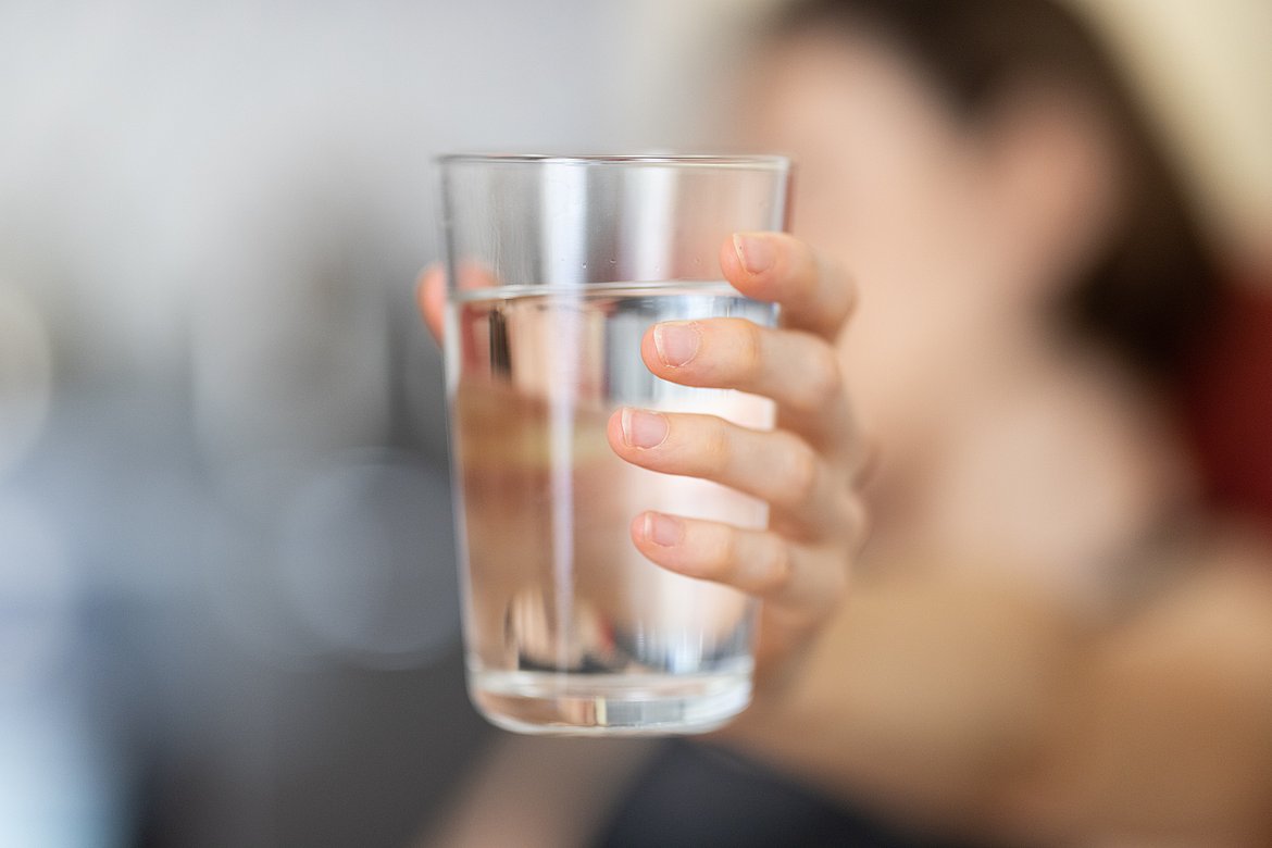 Glas mit Wasser gehalten von einer Hand