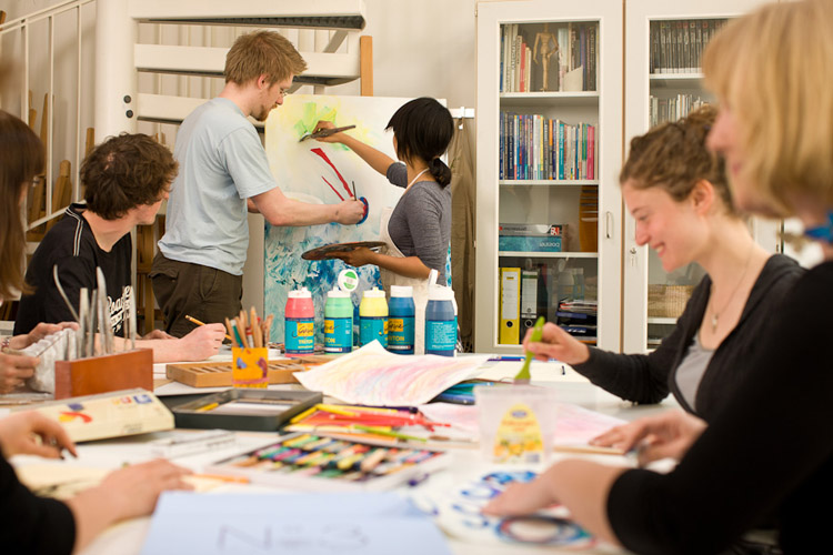 Eine Gruppe Studierender befindet sich in der Kunstwerkstatt. Sie basteln und mit verschiedenen Materialien.