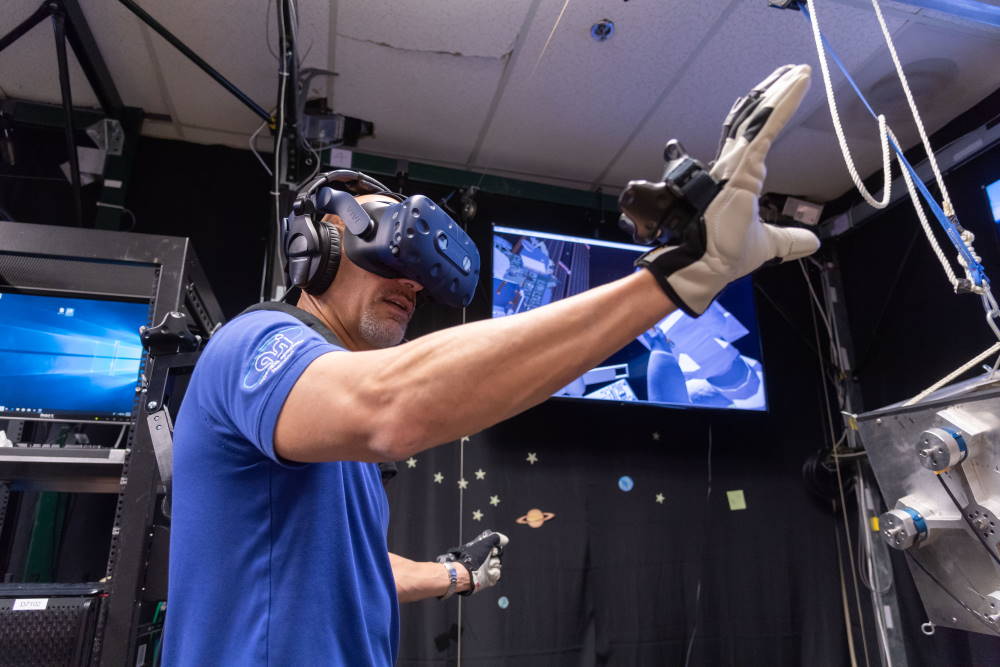 Das Foto zeigt das Astronautentraining mit VR-Headset und VR-Handschuhen