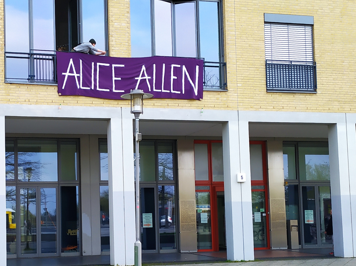 Das Gebäude der Hochschule mit dem Banner in Lila Farbe. Auf dem Banner steht "ALICE ALLEN". 