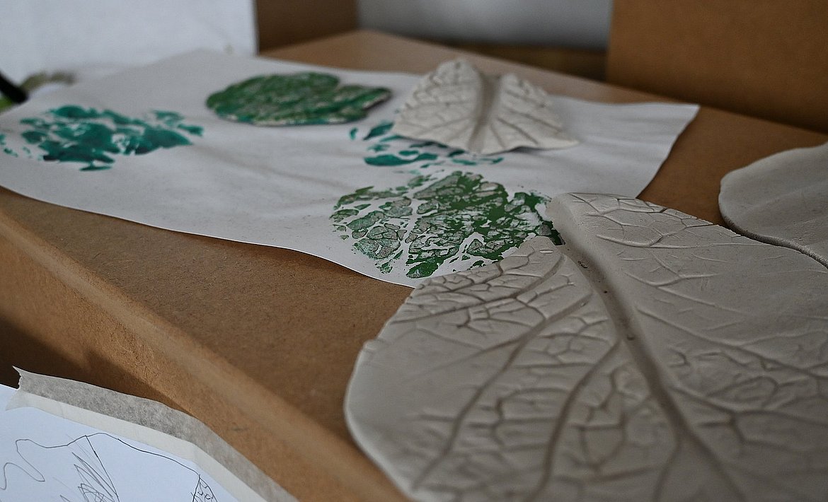 Auf dem Bild ist ein negativ Abdruck von einem Kohlblatt in Tonerde sowie ein Farbabdruck eines Kohlblattes auf Papier zu sehen