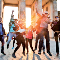 Gruppenfoto vor dem Brandenburger Tor: Eine Gruppe Studierender springt kollektiv in die Luft.