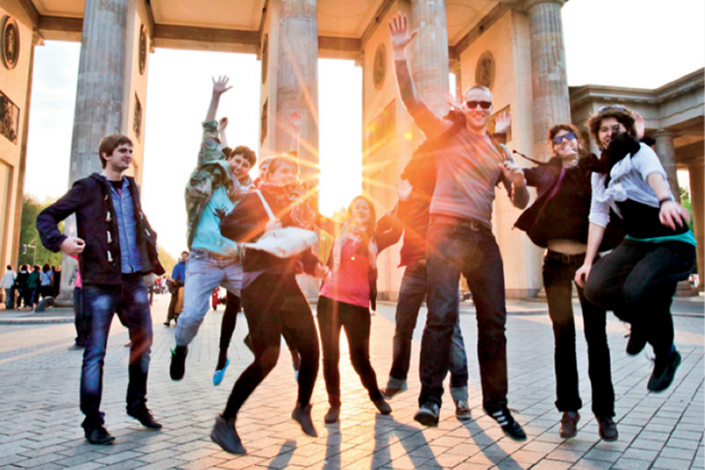 Gruppenfoto vor dem Brandenburger Tor: Eine Gruppe Studierender springt kollektiv in die Luft.