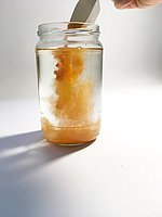 Orangene Farbpigmente werden in Wasser geschüttet