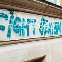 Der Schriftzug "Fight Sexism!" in türkis auf einer Hausfassade.