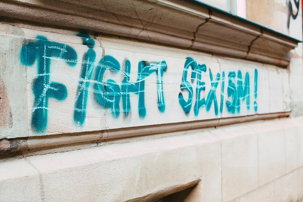 Der Schriftzug "Fight Sexism!" in türkis auf einer Hausfassade.