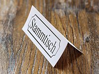 Auf dem Bild sieht man einen Tisch, auf dem ein Schild steht mit der Aufschrift "Stammtisch". 
