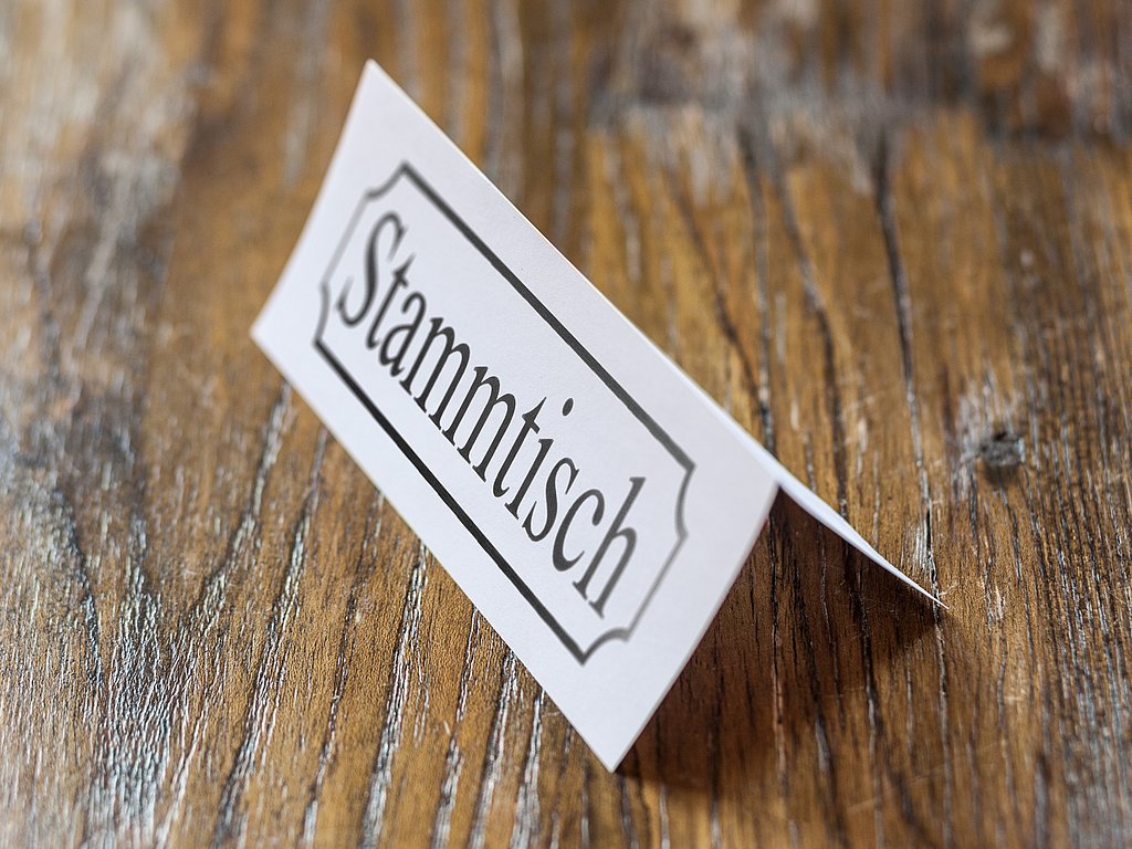 Auf dem Bild sieht man einen Tisch, auf dem ein Schild steht mit der Aufschrift "Stammtisch". 