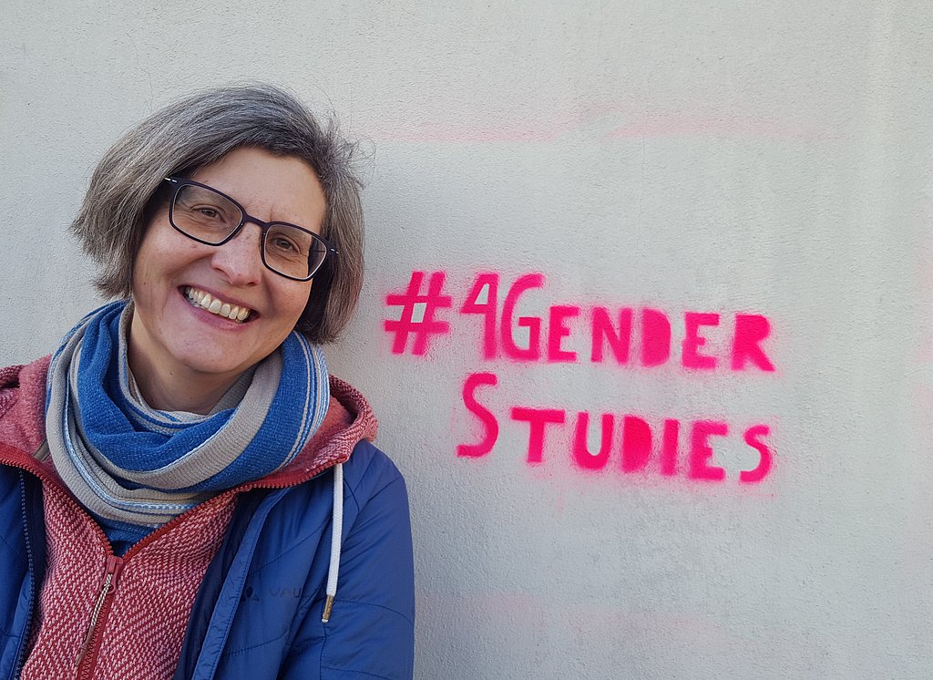 Porträtfoto von Nadja Damm im Hintergund gesprüht der #4GenderStudies der Hashtag zum Wissenschaftstag unterstützt von der Arbeitsgemeinschaft der Frauen- und Geschlechterforschungseinrichtungen Berliner Hochschulen (afg)