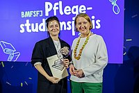 Auf dem Foto sind die ASH-Alumna Christianna Quack und Bundesfamilienministerin Lisa Paus zu sehen. Christianna hält den Pflegestudiumspreis 2024 in der Hand.