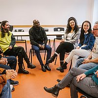 Studierende sitzen in einem Stuhlkreis in einem Seminarraum