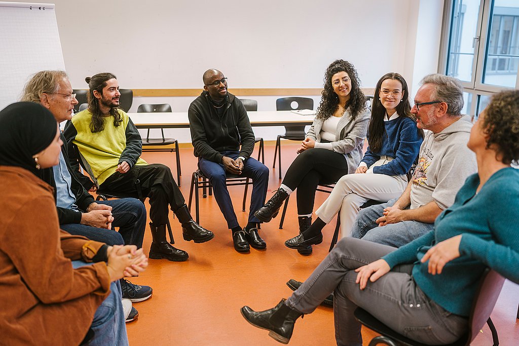 Studierende sitzen in einem Stuhlkreis in einem Seminarraum