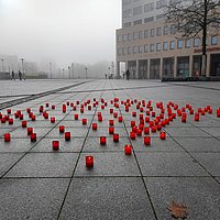 129 brennende Kerzen stehen auf dem Platz vor dem Marzahn-Hellersdorfer Rathaus