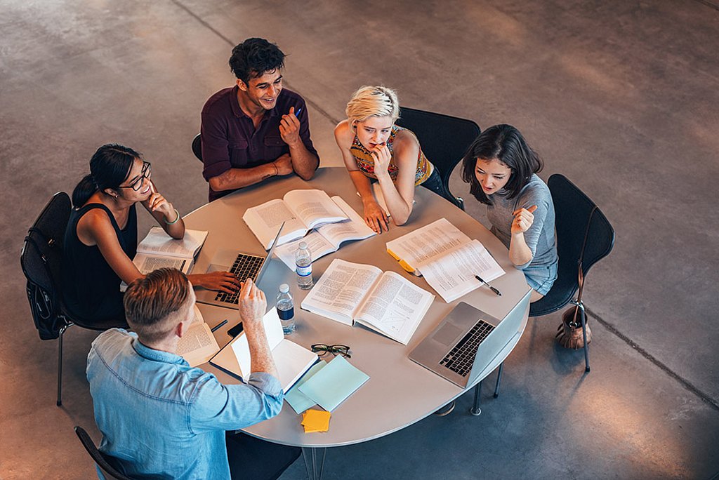 Studierende sitzen an einem großen runden Tisch und lernen miteinander.