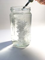 Weiße Tusche wird in Wasser getropft