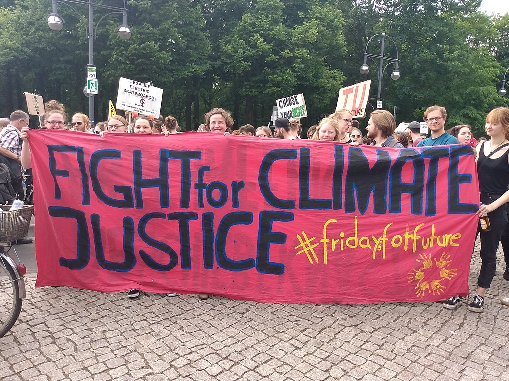 Studierende halten auf einer Demo ein Banner hoch auf dem Fight for Climate Justice steht