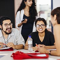 Drei Studierende des Master of Arts Studiengangs Gestión de Conflictos Interculturales sitzen an einem Tisch und unterhalten sich.