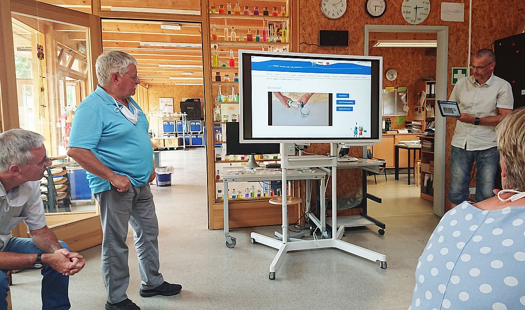 Blick aus dem Publikum auf Referenten und Monitor, auf dem Helleum Zuhause vorgestellt wird