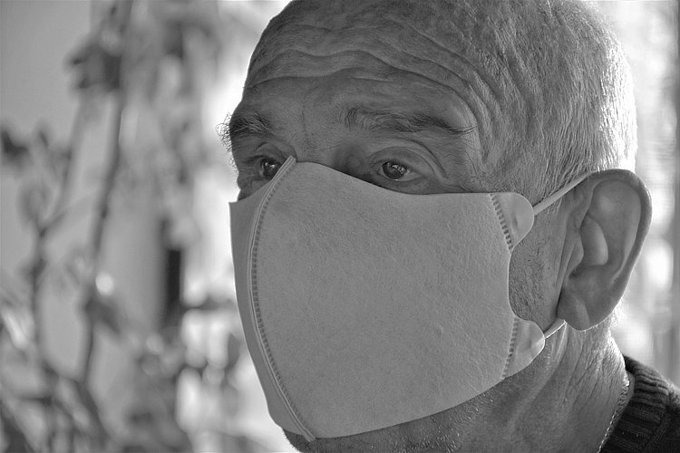 Schwarz-Weiß-Bild: Kopf eines alten Mannes mit Maske auf