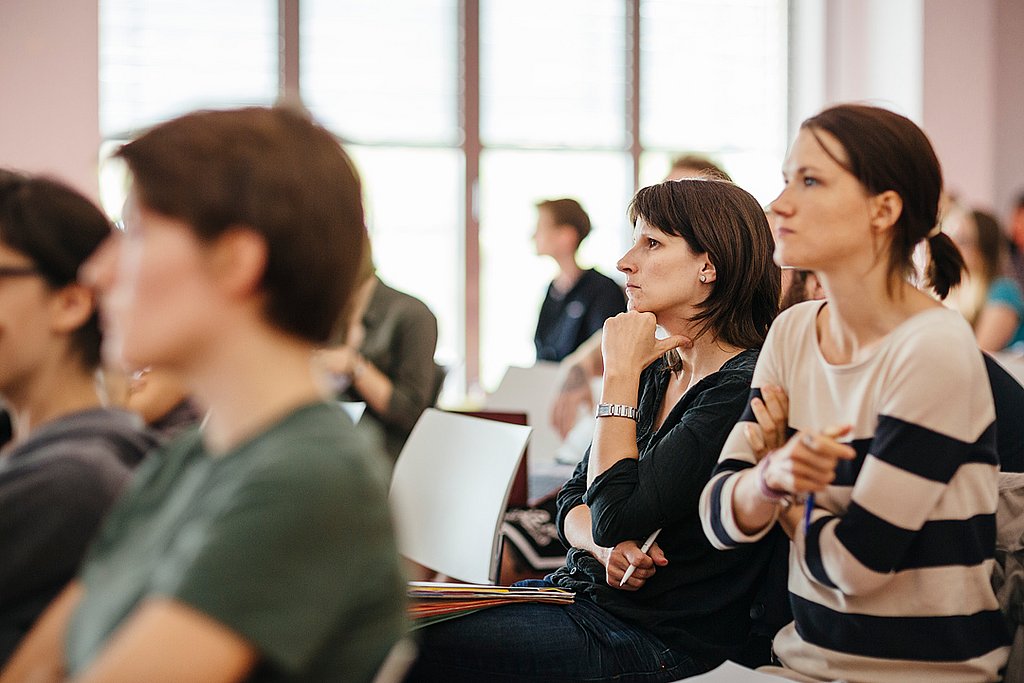 Studierende sitzen in einer Vorlesung im Audimax und gucken kritisch