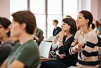 Studierende sitzen in einer Vorlesung im Audimax und gucken kritisch