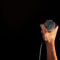 Hand mit Mikrophon vor schwarzem Hintergrund