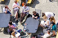 Studierende genießen die Sonne im Innenhof des Hochschulgebäudes.