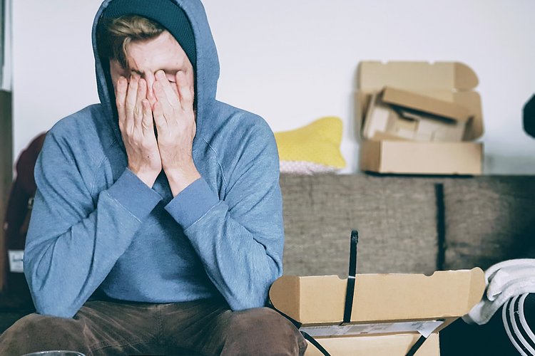 Arbeitsbelastung Überfordert wirkender junger Mann mit Hände vor dem Gesicht