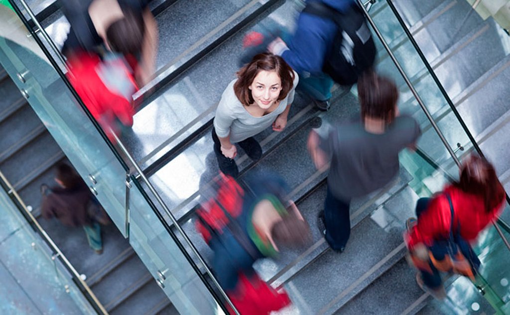 Eine Frau steht auf einer Treppe und schaut nach oben in die Kamera