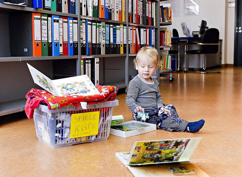 Ein kleines Kind spielt mit Spielsachen aus einer Spielsachenbox in der Bibliothek der ASH Berlin