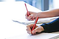 Aufnahme von zwei Händen mit Kugelschreiben, welche Mitschriften notieren.