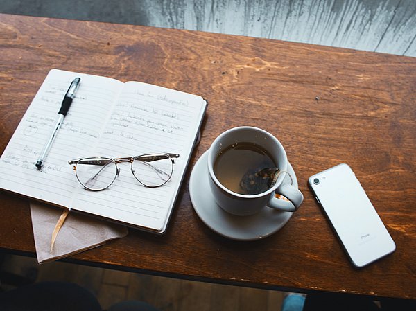 Kaffe und Unterlagen auf Tischplatte