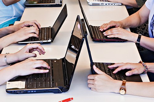 Detailansicht mehrerer Laptops, an denen gearbeitet wird.