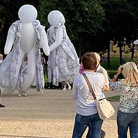 Besucher und Besucherinnen der Potsdamer Schlössernacht schauen sich draussen eine Performance an 