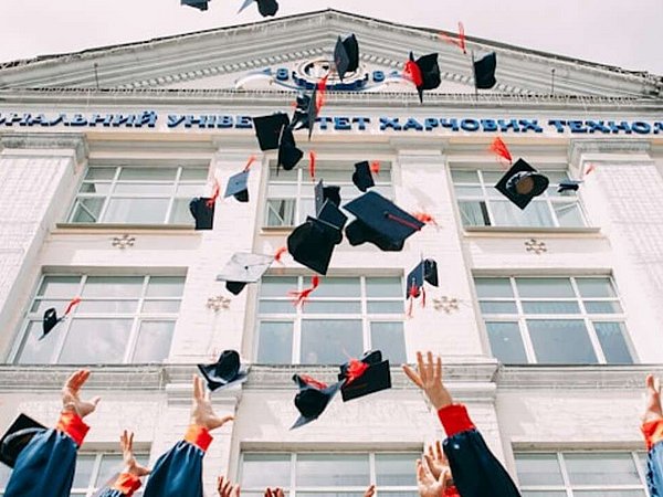 Graduiertenkappen in die Luft geworfen vor Haus