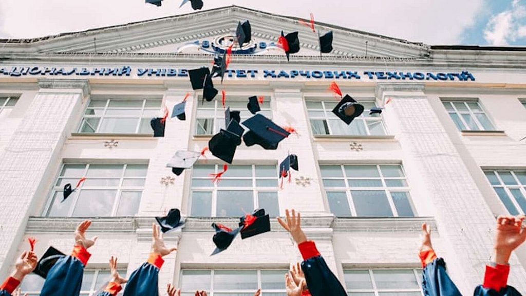 Graduiertenkappen werden in die Luft geworfen
