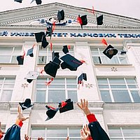 Graduiertenkappen werden in die Luft geworfen