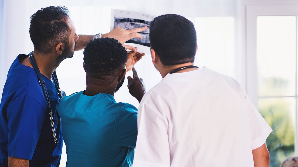 Drei health care professionals, die eine Ultraschallaufnahme begutachten