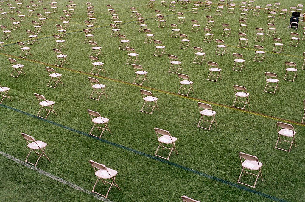 Stühle stehen mit Abstand auf dem Rasen eines Sportfeldes