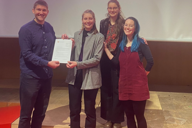 Das Foto zeigt Dr. Yannick Liedholz bei der Ehrung von drei Studierenden.