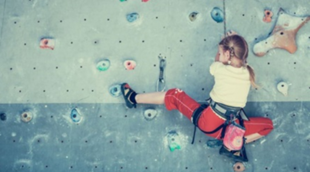 Ein Kind klettert an einer Kletterwand