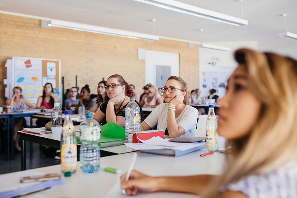 Studierende der ASH Berlin sitzen in einem Seminarraum und hören einem Vortrag zu.