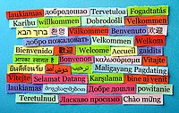 Auf der Abbildung sind viele kleine Tafeln zu sehen, auf der "Willkommen" in vielen verschiedenen europäischen und außereuropäischen Sprachen geschrieben steht.  