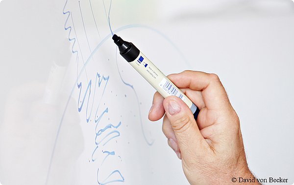 eine Person mal mit einem Stift auf einem FlipChart