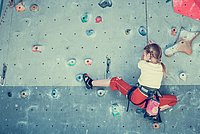 Mädchen klettert an einer Kletterwand hoch