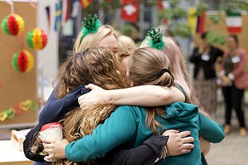 Four girls from different nationalities are hugging.