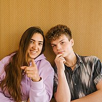 Zwei Studierende lachen in die Kamera