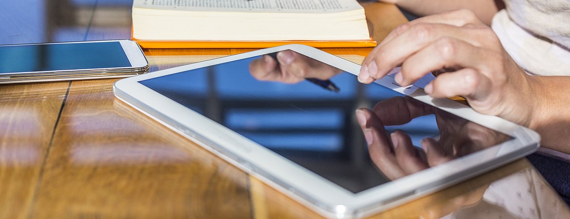 Eine Studentin arbeitet gleichzeitig mit Buch Tablet und Smartphone