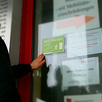 Eine Person bringt am Haupteingang der ASH Berlin den "Noteingang"-Aufkleber an. 